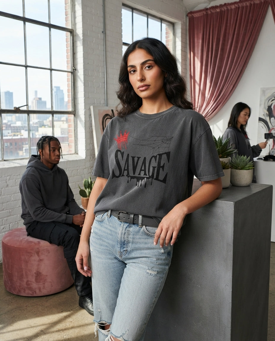 A person wearing a heavyweight charcoal graphic t-shirt with a crown design in an urban loft space with rose and white interi